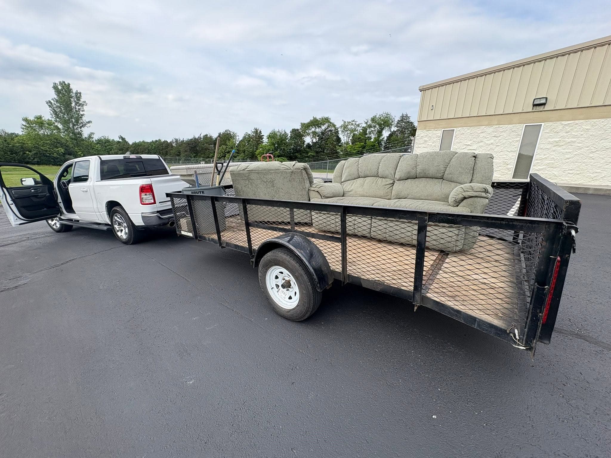 White pickup truck towing a trailer loaded with a couch and loveseat